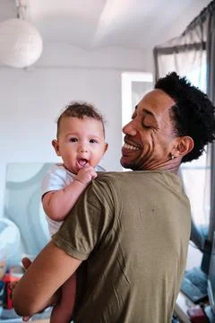 Caring man smiling while holding up his baby. Stock Photos