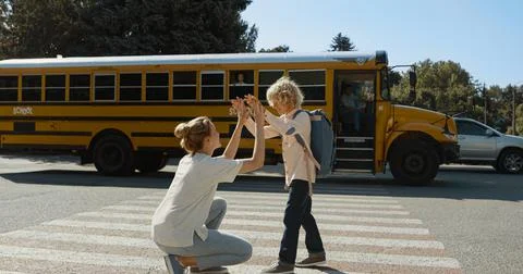 Caring mother escorting son to school bus. Mom watch child boarding schoolbus. Stock Photos