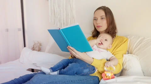 Caring mother reading a book to cute baby girl, bonding time and early learning 스톡 동영상 320244334