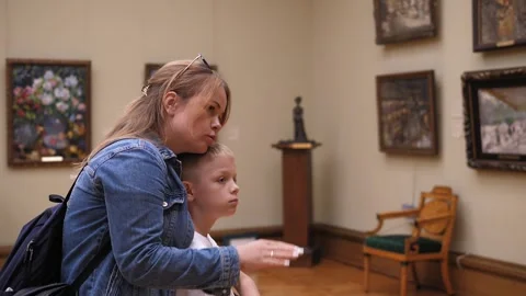 A caring mother with a young son in an art gallery, they look at paintings. Stock Footage 247126817