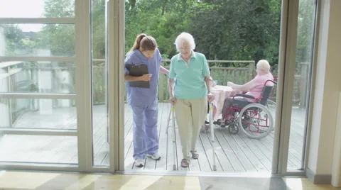 Caring nurse helping elderly female patient to walk in hospital or care home Stock Footage 44669663