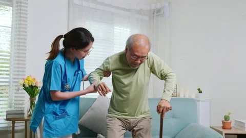 Caring nurse helping supporting senior disabled man to stand up with walking Stock Footage 215518877