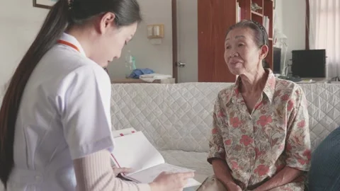 Caring Nurse Interacting with Elderly Patient at Home Stock Footage 313942375