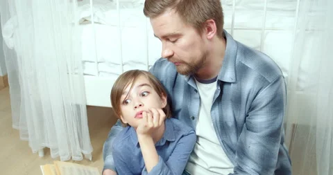 Caring parent dad is reading interesting book to his little son in the bedroom Stock Footage 131853956
