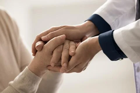 Caring professional doctor hold patient hand in clinic during visit Stock Photos
