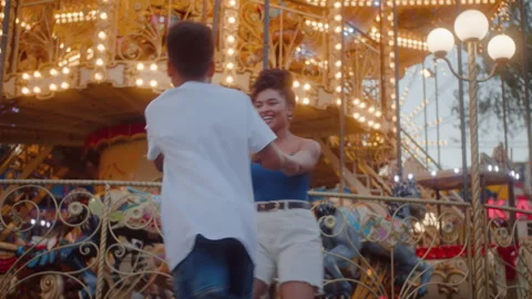 Caring sister having fun with brother next to carousel Stock Footage 280261010