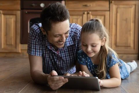 Caring young father using digital computer tablet with little daughter. Stock Photos