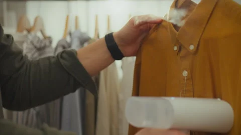 A caring young man working in a stylish boutique tidies up his clothes using Stock Footage 266807816