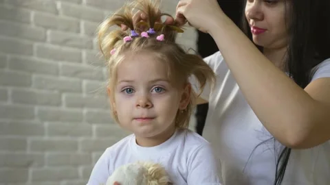 A caring young mother combs clean hair for her child. The girl makes a beautiful Stock Footage 136297352