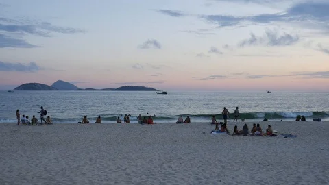 Carioca Brazilians relax while some play altinho keepy uppy beach football Stock Footage 104663747