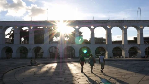 Carioca pedestrians with sunrays backlighting the 19th-century colonial Lapa Stock Footage 105298385