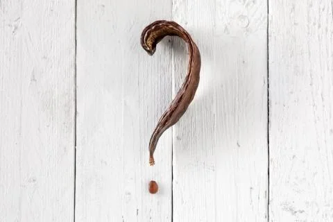 Carob Pod with Question Mark Shape on White Wood Stock Photos