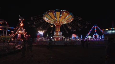 Carousel spinning on street fun fair at night with crowd of people Stock Footage 100246221