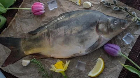 Carp for the festive Easter table with rosemary and lemon on crumpled paper. Stock Photos