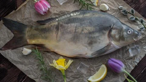 Carp for the festive Easter table with rosemary and lemon on crumpled paper. Stock Photos