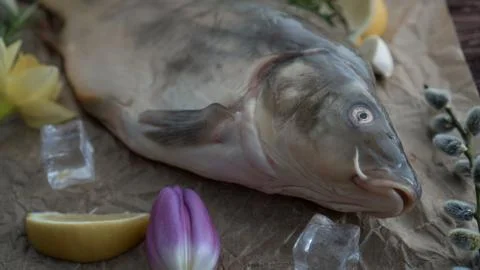 Carp for the festive Easter table with rosemary and lemon on crumpled paper. Stock Photos