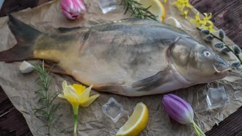 Carp for the festive Easter table with rosemary and lemon on crumpled paper. Stock Photos
