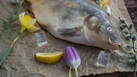 Carp for the festive Easter table with rosemary and lemon on crumpled paper. Stock Photos