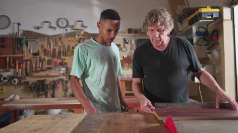 Carpenter and apprentice working at workshop, teacher orienting young man w.. Video stock 246766221