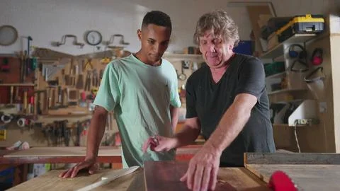 Carpenter and apprentice working at workshop, teacher orienting young man w.. Stock Photos
