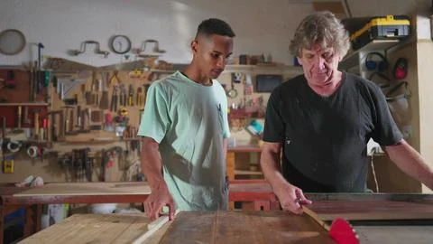 Carpenter and apprentice working at workshop, teacher orienting young man w.. Stock Photos