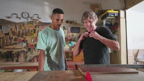 Carpenter and apprentice working at workshop, teacher orienting young man w.. Stock Photos