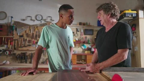 Carpenter and apprentice working at workshop, teacher orienting young man w.. Stock Photos
