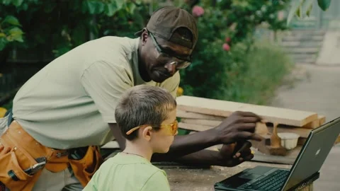 Carpenter and boy work with wood following video instruction Stock Footage 200779676