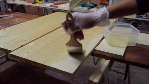 Carpenter applying protective varnish to a wooden board with a brush Stock Footage 335680480