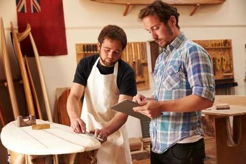Carpenter With Apprentice Making Bespoke Wooden Surfboard Foto stock