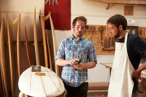 Carpenter With Apprentice Making Bespoke Wooden Surfboard Stock Photos