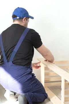 A carpenter assembles a wooden structure from slats. Carpentry work Stock Photos