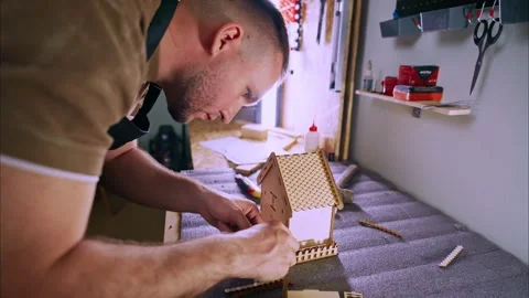 Carpenter assembling small wooden house in workshop Stock Footage 308932685