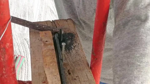 A carpenter is bending rebar into curves using special equipment to create .. Stock Footage 300074559