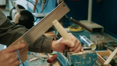 Carpenter in carpentry workshop saws wooden stick with hand saw. Furniture Stock Footage 262611219