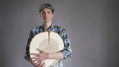 A carpenter in a ceached shirt and goggles, with a felling tree in his hands Stock Footage 130636861