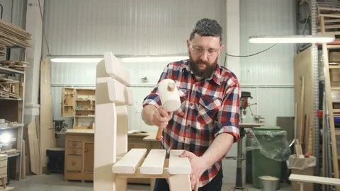 Carpenter in a checkered shirt with a beard in the workshop crosses his hands Stock Footage 88962143