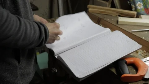 Carpenter is checking the notebook for blueprints of wooden constructions Vidéo 119669624