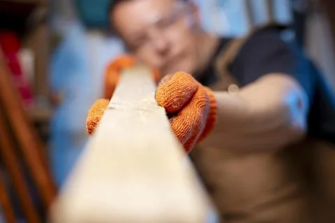 A carpenter checking smoothness of wood material. Woodworker preparing planks Stock Photos