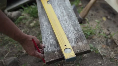 The carpenter checks that the edge of the board is parallel and draws a line Stock-Footage 141306276
