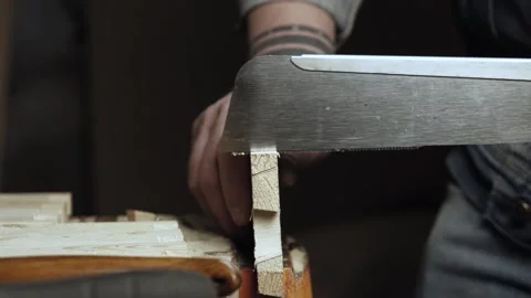 A carpenter cuts out a dovetail on a pine board with a hand saw. woodworker m Stock Footage 166341049