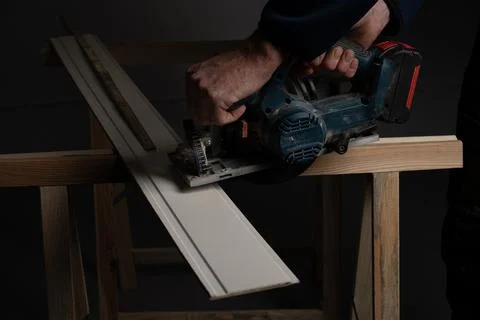 Carpenter cutting decorative wall panel board with cordless circular saw Foto stock