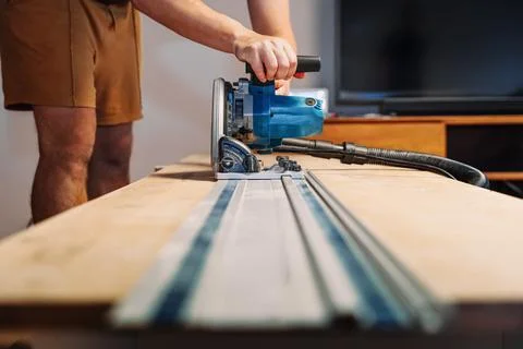 Carpenter Cutting Wooden Panel with Electric Circular Saw Using Track Indoors Stock Photos