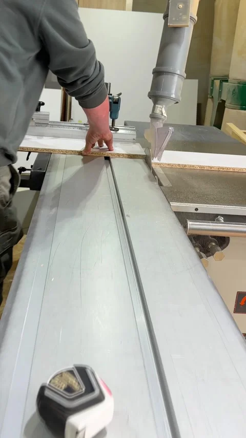 Carpenter cutting a wooden panel on a sliding table saw in a workshop. Man Stock Footage 339432284