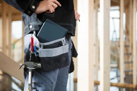 Carpenter With Digital Tablet And Tools In Bag At Site Stock Photos