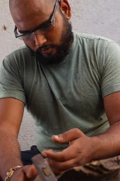 Carpenter is doing woodwork with his hammer and Chisel with Safety glass Stock Photos
