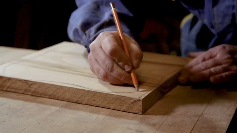 Carpenter draws with a pencil cutting line on a piece of wood Vidéo 100744112