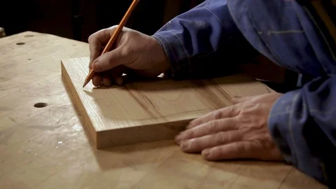 Carpenter draws the shape of the product on a piece of wood Vidéo 100744663