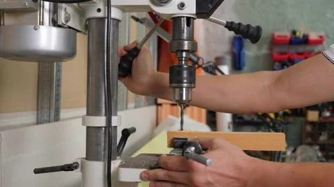 A carpenter drilling a board with an automatic drill in a carpentry workshop. Stock Footage 312436489