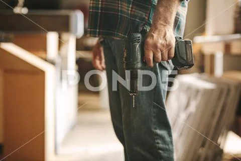 Carpenter with drilling machine in hand at workshop Stock Photos